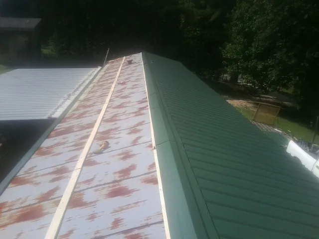 Old rusted panels beside newly installed green metal roofing — Wind Damage Roof Repair by Roofing Brothers in Battle Creek