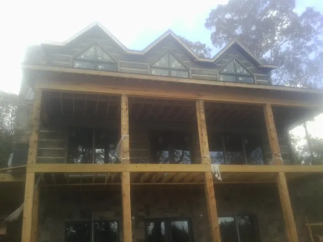 Dormers and porch framing on a large log home under construction — Roof Coating work by our crew in Battle Creek