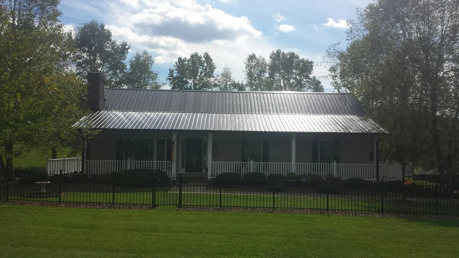 Gray metal roof on a brick ranch with a full width front porch — Gutter Guard Installation work by our crew in Battle Creek