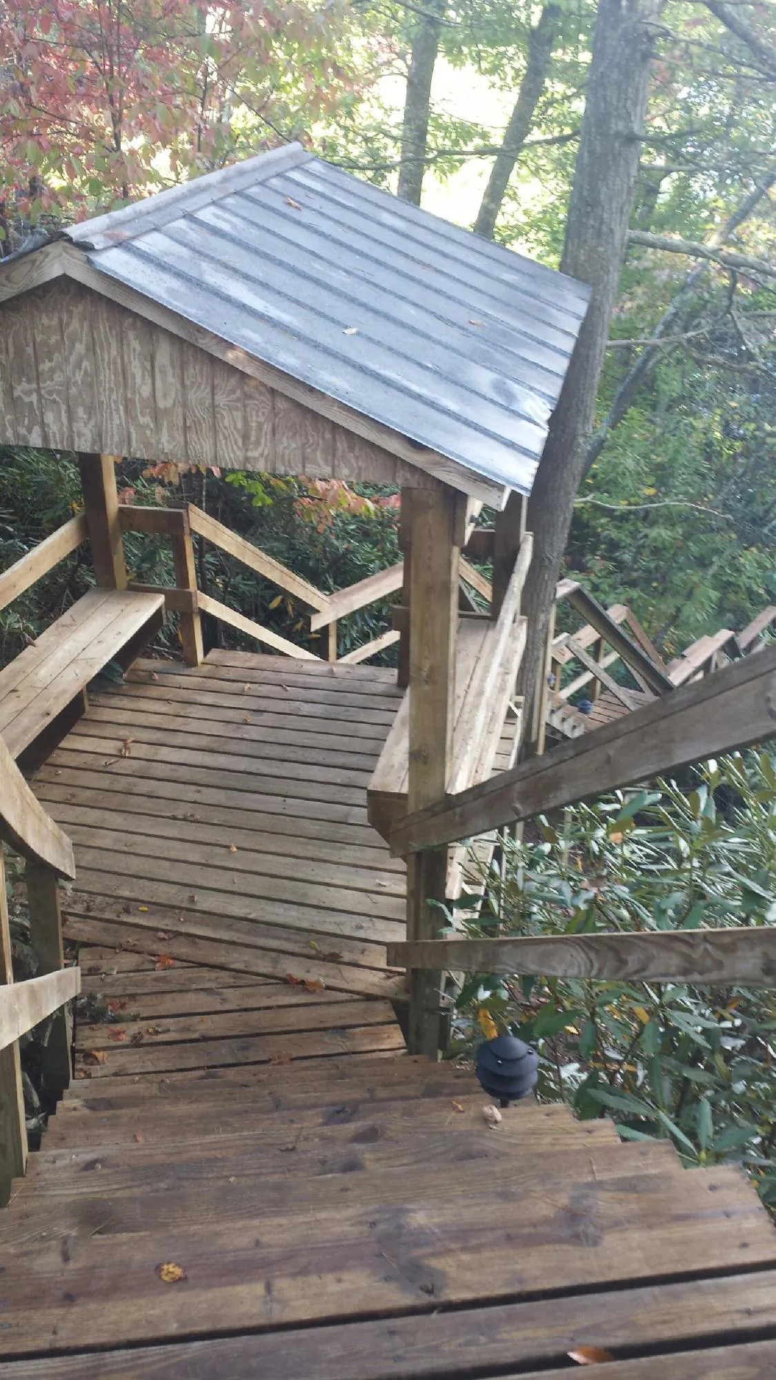 Metal roofed shelter over wooden steps on a wooded walkway — Skylight Repair & Installation work by our crew in Battle Creek